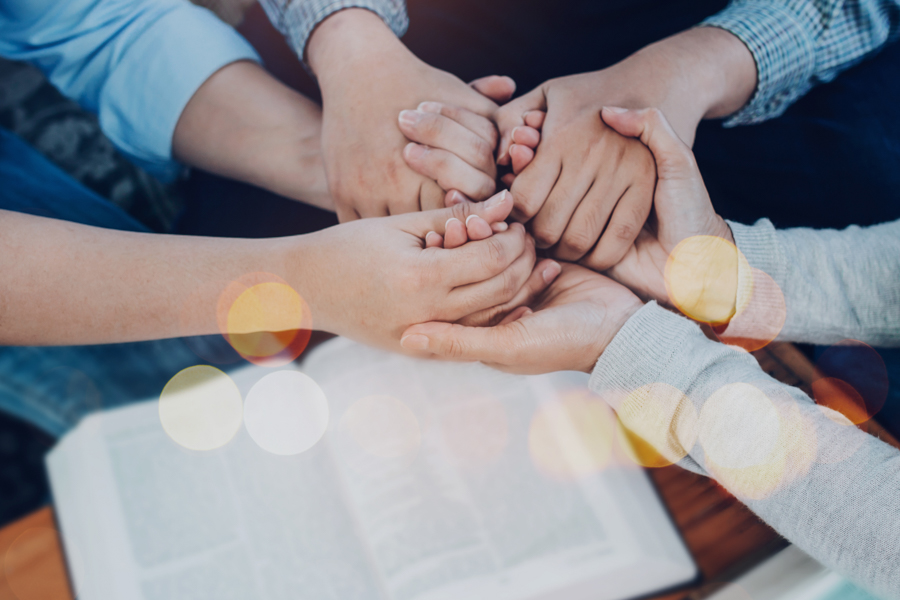 Close up of people group holding hand and pray together over a Close up of people group holding hand and pray together over a